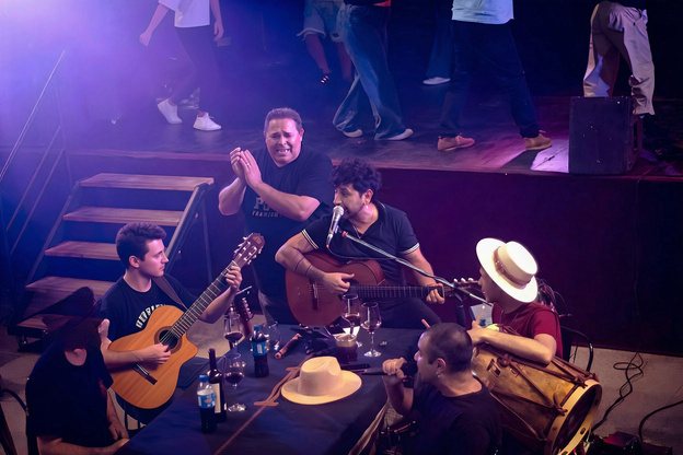 Músicos con guitarras y sombreros alrededor de la mesa