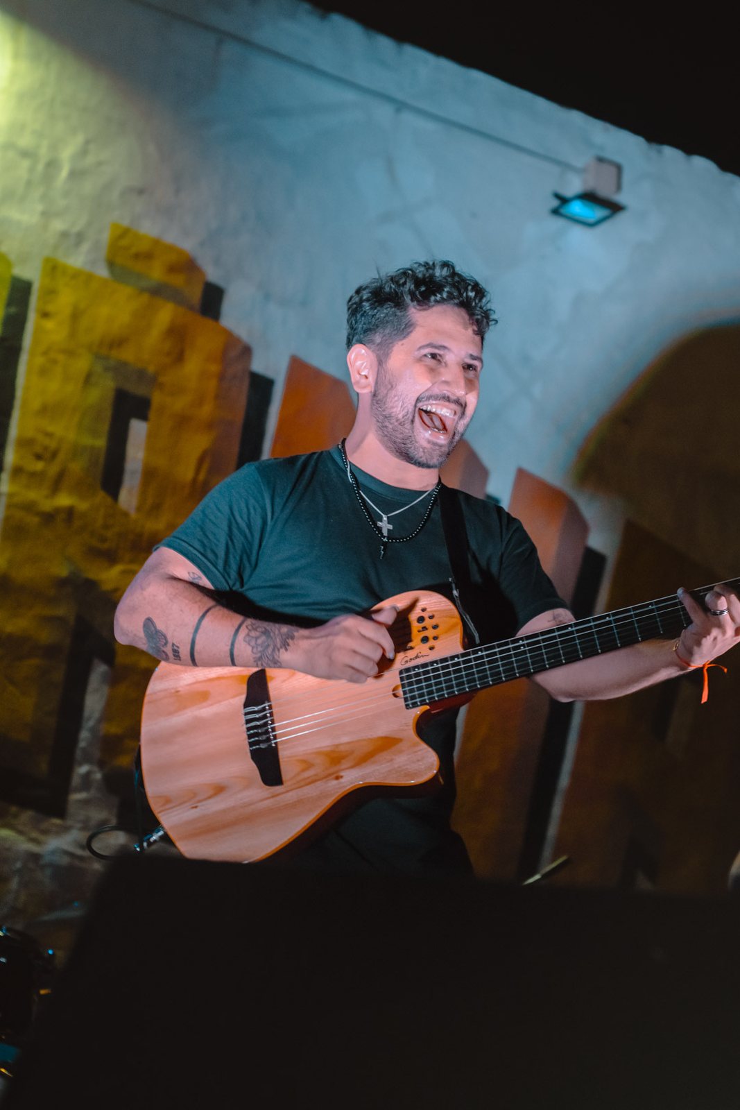 Ramón Álvarez con su guitarra frente a un mural