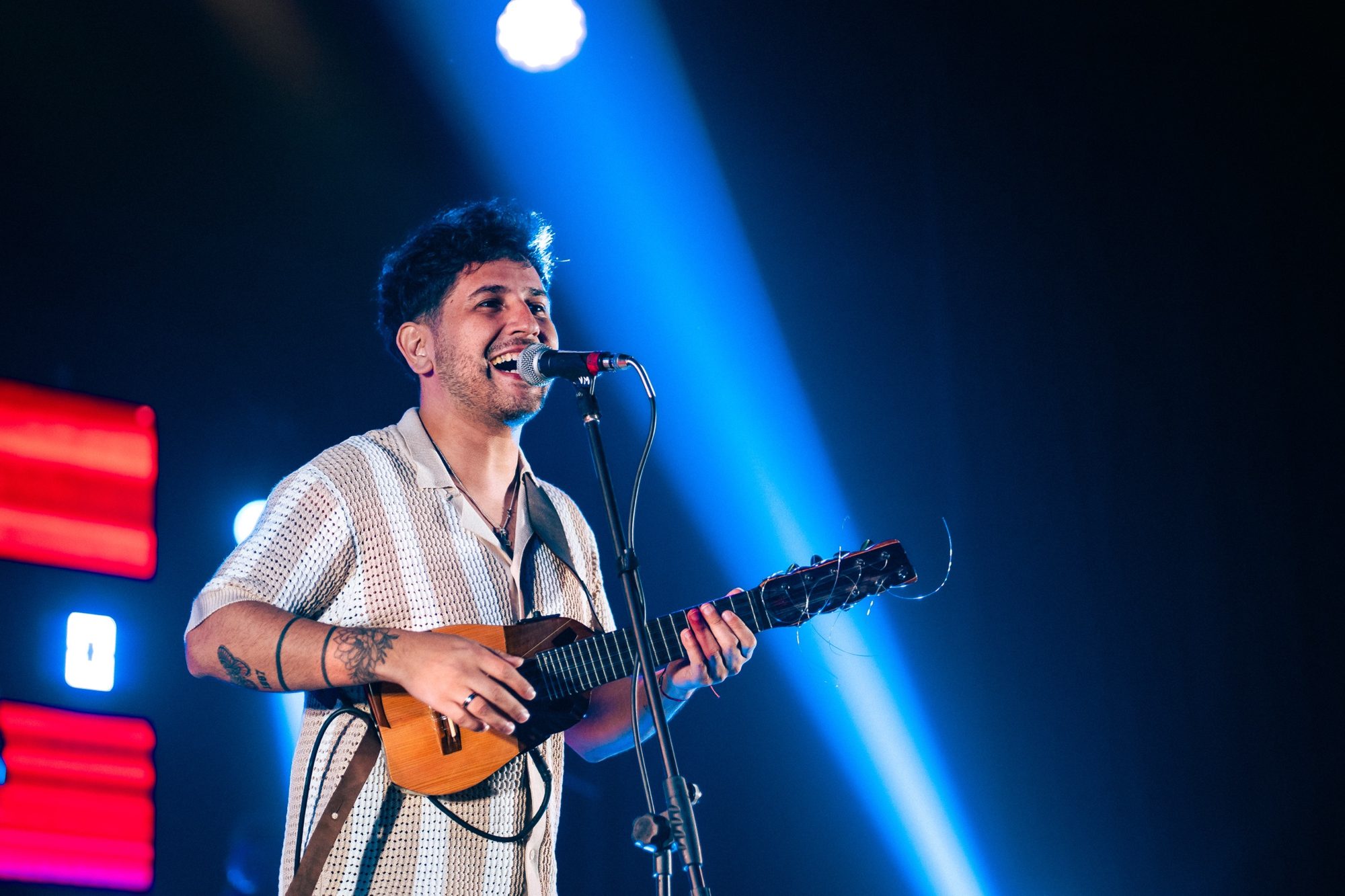 Ramón Álvarez cantando y tocando el charango bajo un haz de luz azul